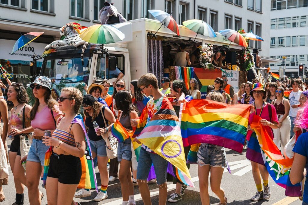 Photo by Ilia Bronskiy a group of people walking down a street holding rainbow flags